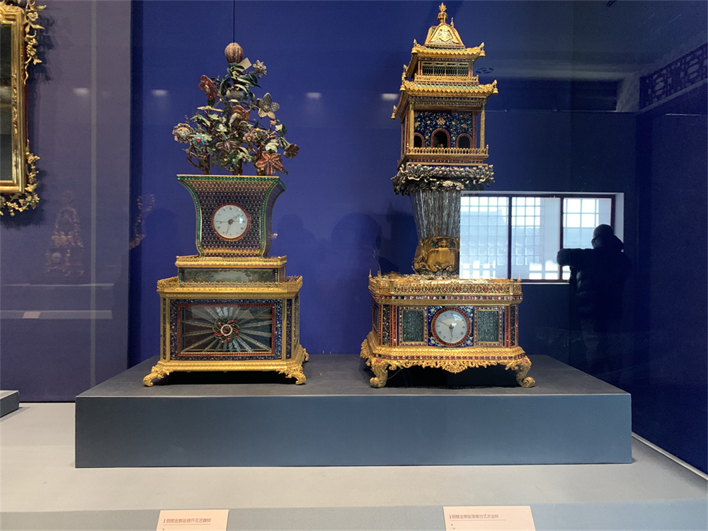 铜镀金嵌珐琅开花活蝶钟（左）和铜镀金嵌珐琅楼台式水法钟（右）